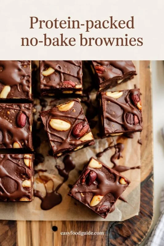 Decadent no-bake protein brownies with chocolate drizzle on a wooden board.