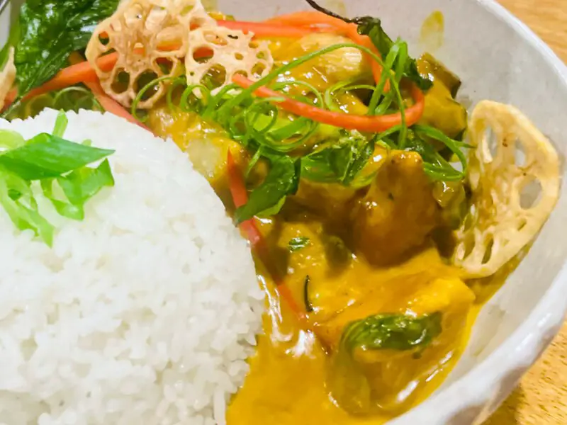 Delicious Vegan Thai Yellow Curry with Coconut Cream & Roasted Vegetables A bowl of Vegan Thai Yellow Curry with roasted pumpkin, eggplant, and green beans, served with rice and garnished.