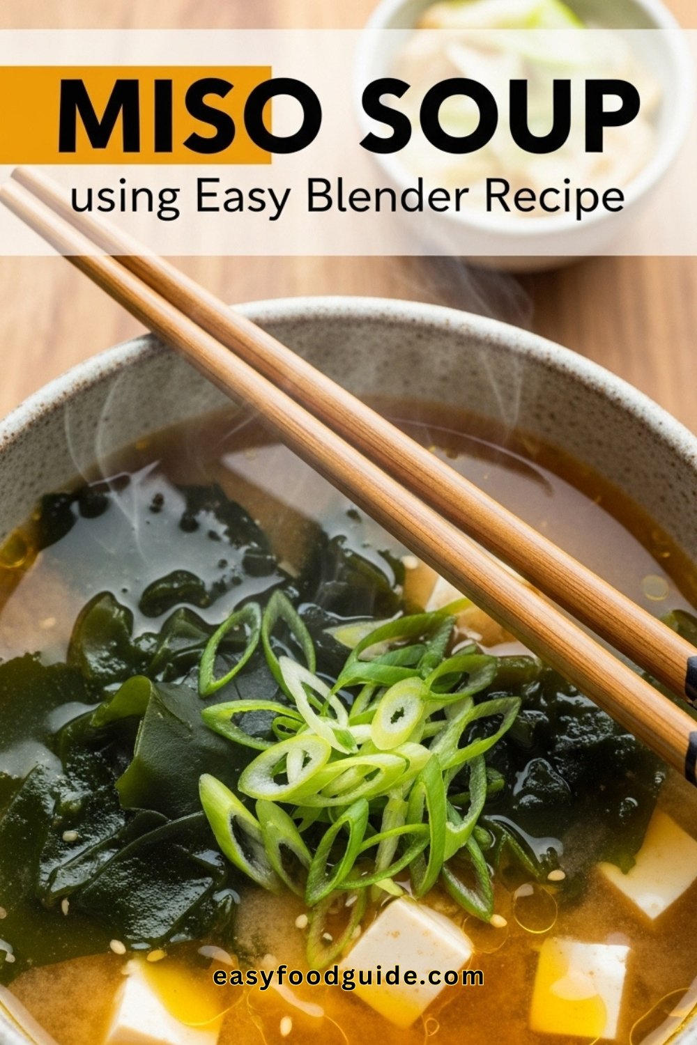A bowl of miso soup with tofu and seaweed, garnished with green onions, served with chopsticks in soft lighting.