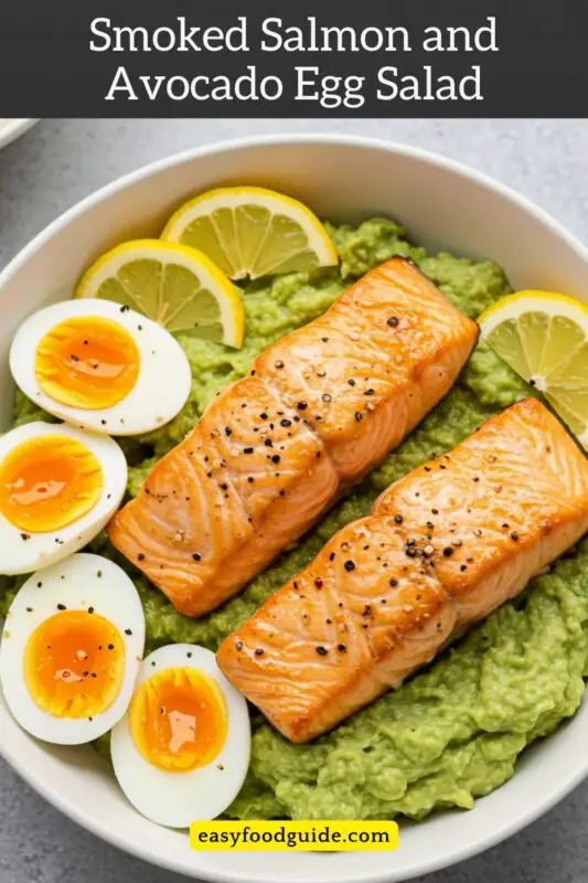 A bowl of Smoked Salmon and Avocado Egg Salad with eggs, avocado, and smoked salmon garnished with lemon wedges.