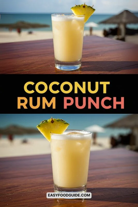 A pitcher of tropical coconut rum punch with fruit garnishes on a wooden table at a beach resort.
