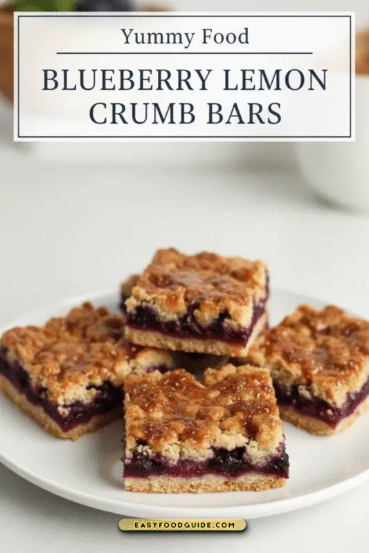 Stacked blueberry lemon crumb bars with a golden topping and fresh blueberries on a checkered surface.