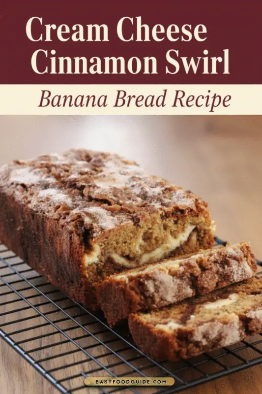 A loaf of cream cheese cinnamon swirl banana bread with a slice revealing marbled swirls, on a wooden board with bananas and cinnamon sticks.