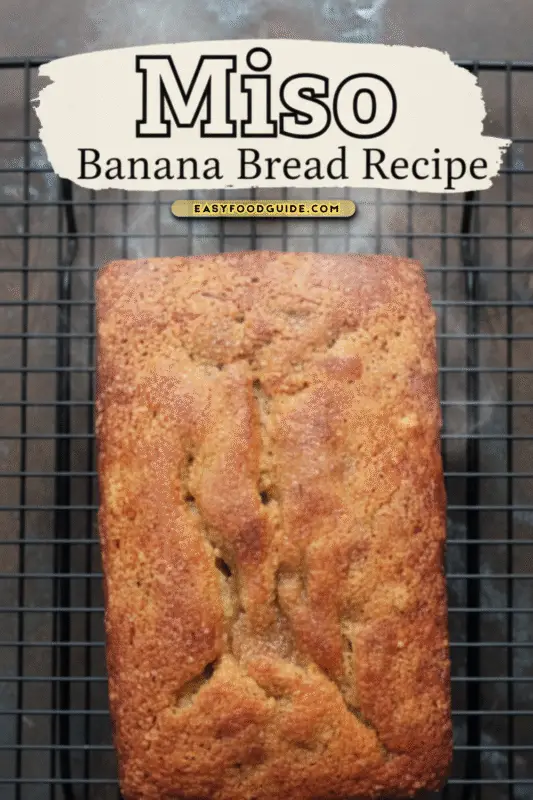 A rustic overhead view of a roasted banana and miso loaf cooling on a wire rack, showcasing its golden-brown crust.
