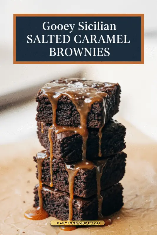 Close-up of gooey chocolate brownies topped with salted caramel sauce on parchment paper.