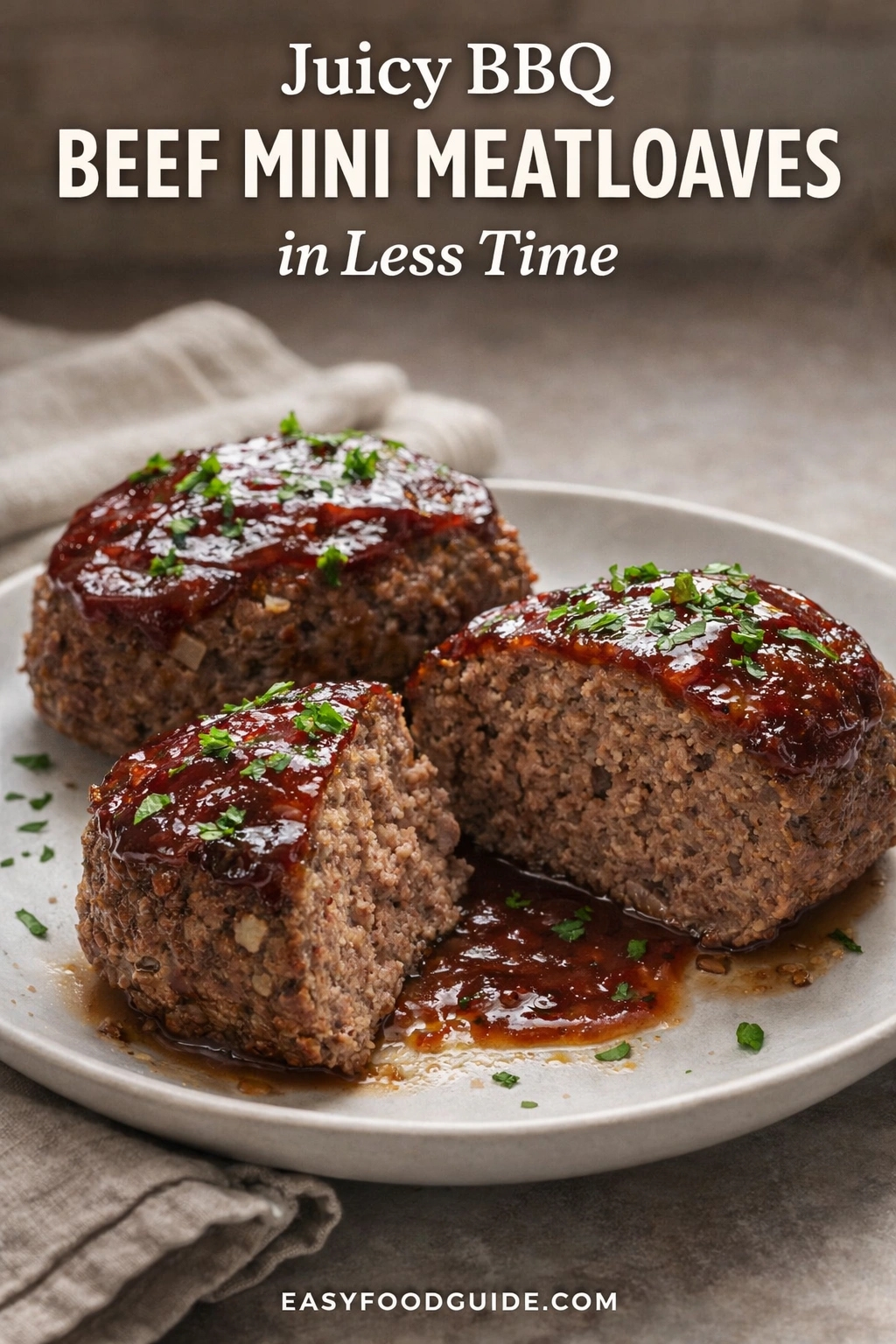 A plate of juicy BBQ beef mini meatloaves, a recipe designed to be made in less time. The small loaves are topped with a glossy barbecue sauce and chopped parsley on a rustic table. Text reads "Juicy BBQ BEEF MINI MEATLOAVES in Less Time," and the website "EASYFOODGUIDE.COM" is at the bottom.