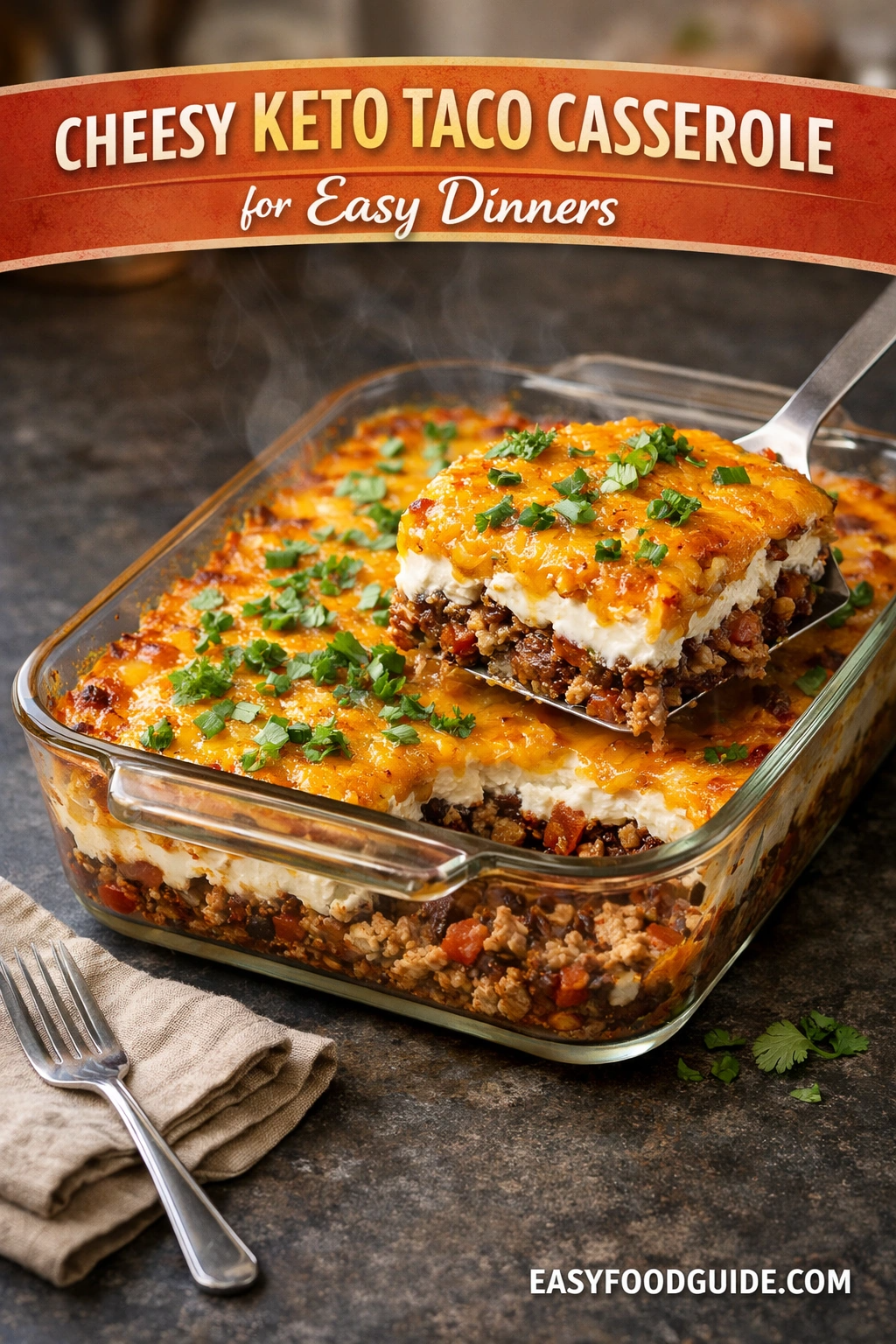 Cheesy keto taco casserole in a glass dish with a portion lifted, showing layered meat, cream, and cheese topped with herbs.