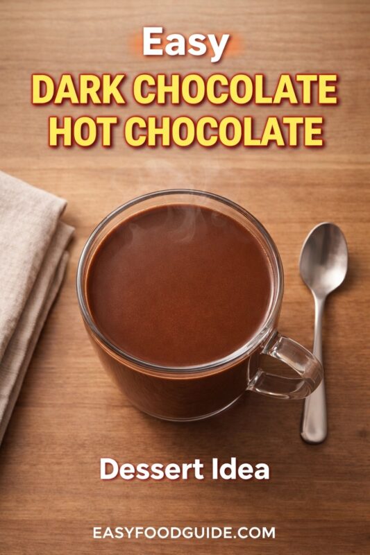 dark-chocolate-hot-chocolate-4 An easy dark chocolate hot chocolate dessert idea, served in a clear glass mug on a wooden surface. The steaming drink is accompanied by a spoon and a folded napkin. Text reads "Easy DARK CHOCOLATE HOT CHOCOLATE Dessert Idea," and the website "EASYFOODGUIDE.COM" is at the bottom.