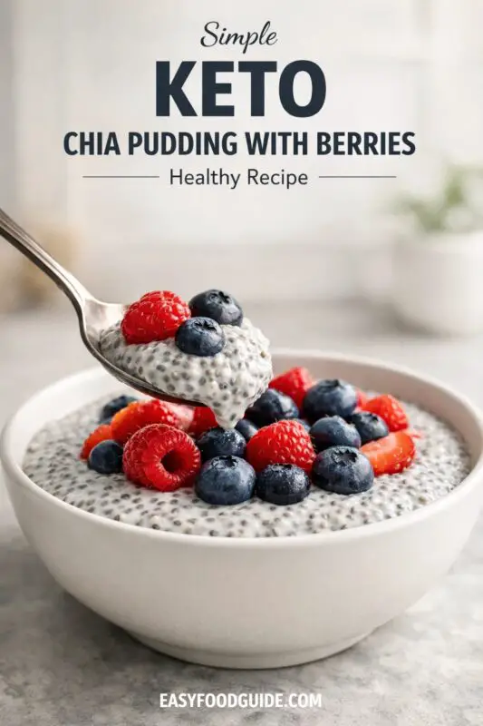 A bowl of chia pudding topped with fresh blueberries and raspberries. A spoonful is held above, showcasing a creamy texture. Text: "Simple Keto Chia Pudding with Berries - Healthy Recipe."