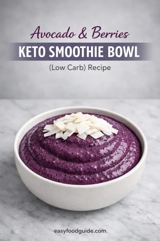 A creamy purple smoothie bowl topped with coconut flakes sits in a white bowl on a marble surface. Text reads "Avocado & Berries Keto Smoothie Bowl."