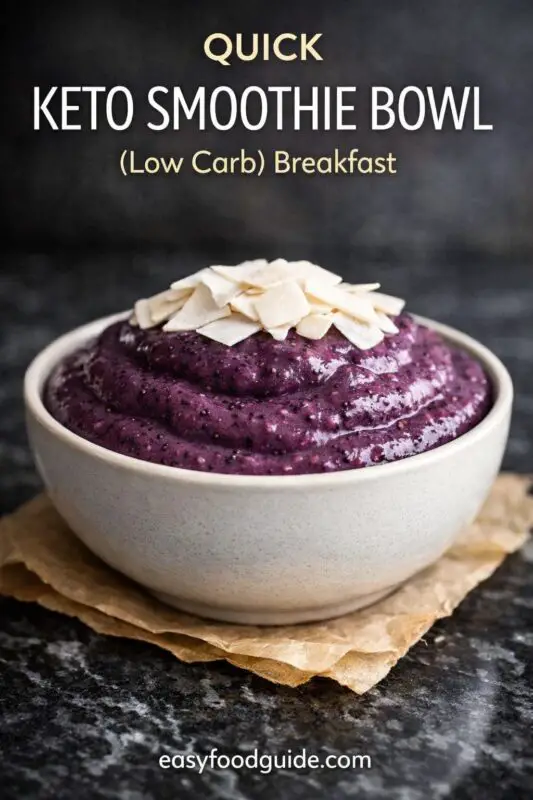 A gray bowl filled with a thick, vibrant purple smoothie, topped with slices of coconut, sits on parchment paper. Text reads "Quick Keto Smoothie Bowl."