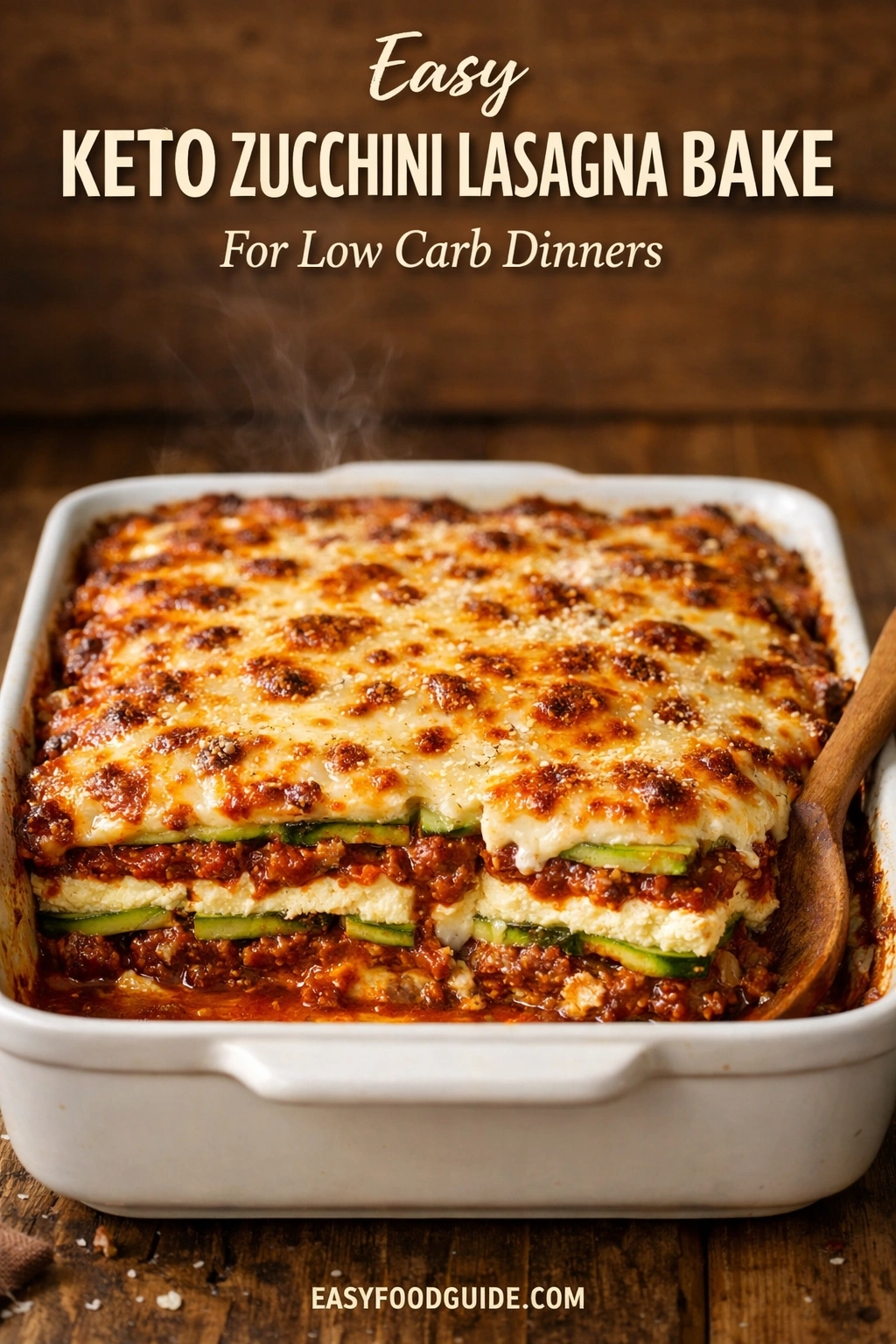 A top-down photograph of a dark, rustic metal sheet pan on a dark wood table, filled with a roasted meal of caramelized sausage slices, golden cauliflower florets, and broccoli, garnished with fresh parsley. Overlaid text at the top reads: 'Crispy' (yellow cursive) followed by 'KETO SAUSAGE & CAULIFLOWER Sheet Pan Dinner' in white. The website 'EASYFOODGUIDE.COM' is at the bottom center.