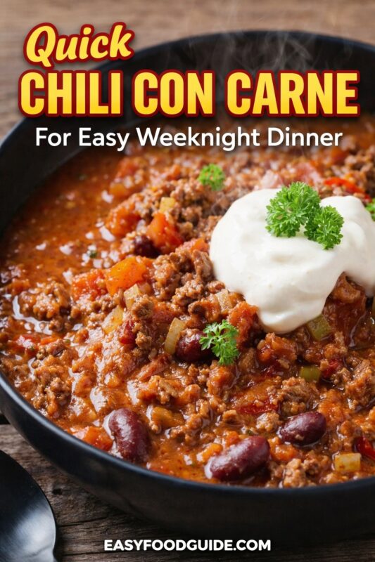 Quick chili con carne in a black bowl: steaming, hearty mix of ground beef, kidney beans, tomatoes, and onions, topped with sour cream and fresh parsley. Text: “Quick Chili Con Carne – For Easy Weeknight Dinner” + EASYFOODGUIDE.COM. Rustic wood surface — fast, flavorful comfort food ready when you need it most.