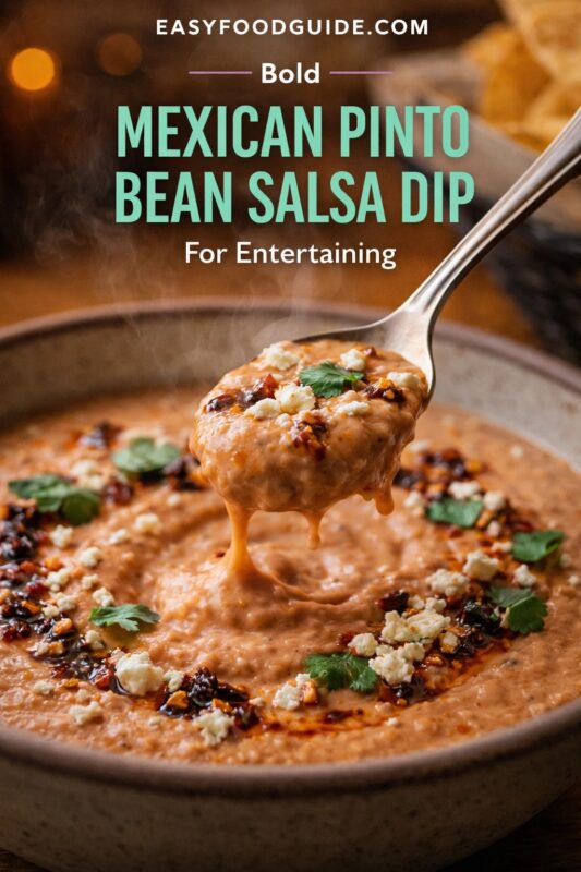 Bold Mexican pinto bean salsa dip: creamy, steaming spoonful topped with crumbled cheese, cilantro, and chili oil. Served in rustic bowl with tortilla chips blurred in background. Text: “Bold Mexican Pinto Bean Salsa Dip – For Entertaining” + EASYFOODGUIDE.COM. Warm lighting, party-ready appetizer vibe.
